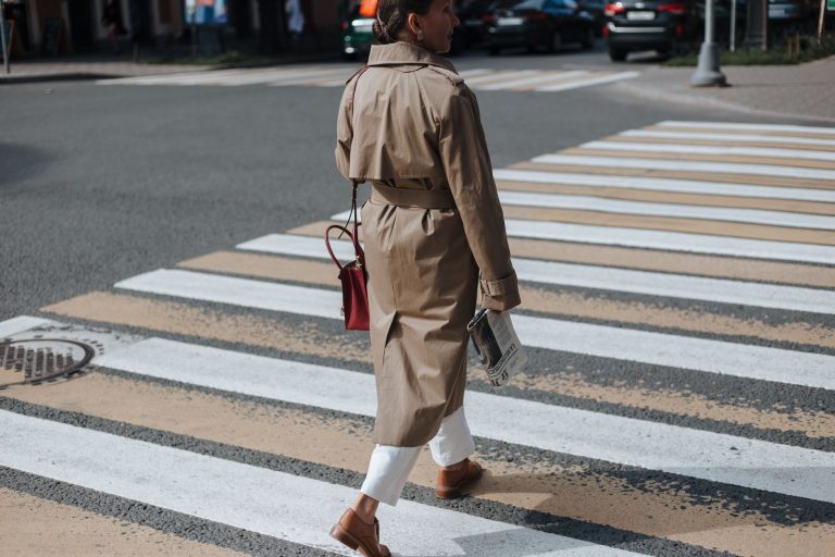 Femme en trench beige dans une rue en automne