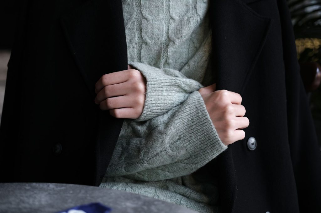 Gros plan sur un pull en laine tenu par des mains, montrant la texture et les mailles