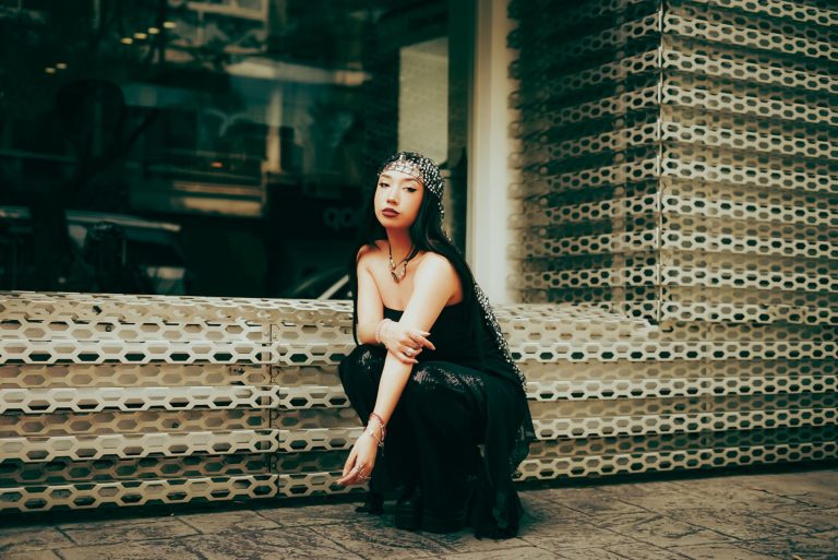 Femme en tenue noire urbaine, mélange de textures et accessoires brillants